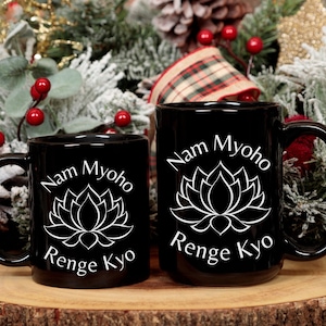 May include: Two black ceramic mugs with white lettering and a lotus flower design. The mugs read "Nam Myoho Renge Kyo".