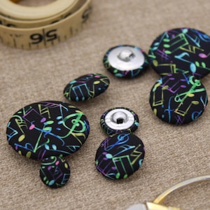 May include: Assortment of colourful fabric buttons with a musical note pattern on a black background. The buttons are 2.5 cm in diameter.