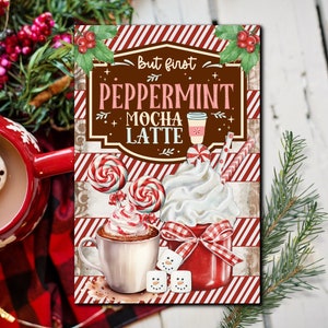 May include: A red and white striped background with a brown sign that says "But first Peppermint Mocha Latte". There is a cup of hot chocolate with whipped cream and candy canes on top. The image is a digital illustration.