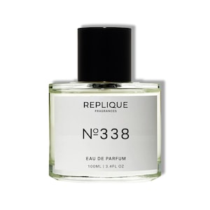 Op de afbeelding: Een doorzichtige glazen fles met Replique Fragrances No. 338 Eau de Parfum. De fles bevat 100 ml.