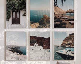 May include: A gallery wall set of six framed landscape photographs featuring Mediterranean coastal scenes, including a dark wooden door with greenery, ocean views, beach umbrellas, white buildings, a church, and a boat on blue water.