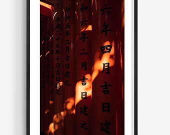 May include: A framed vertical photograph featuring a series of vibrant orange-red torii gates arranged in a row. Each gate is inscribed with black Japanese kanji characters. Sunlight creates dappled shadows across the smooth, cylindrical surfaces.