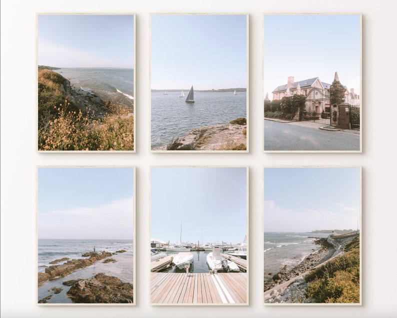 May include: A set of six framed photographs featuring coastal scenes. The photos depict a rocky coastline, a sailboat on the water, a house with a white facade, and a harbor with boats docked. The photos are all in a light blue and white color scheme.