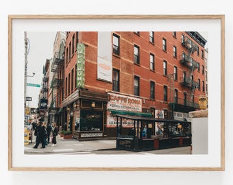 May include: A framed photograph of a red brick building on a city street corner featuring a green vertical sign that reads Caffe Roma and a matching black outdoor dining structure with the text Caffe Roma printed on the side of the enclosure.