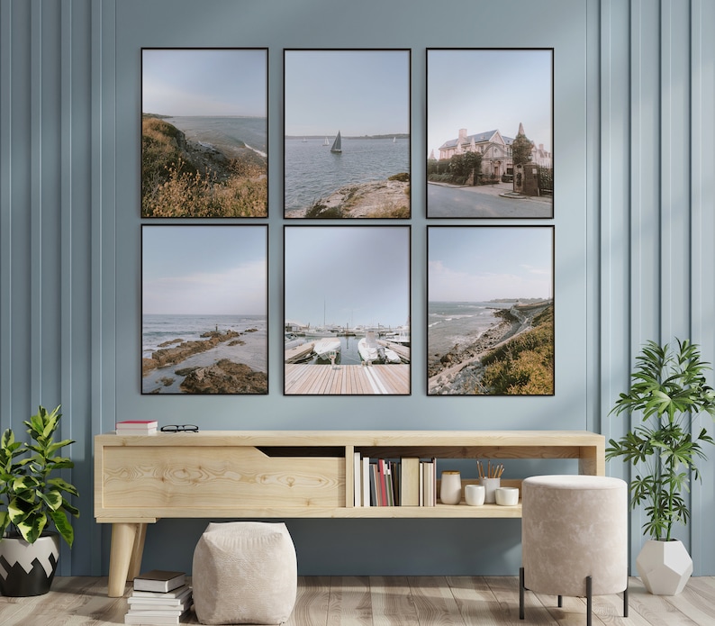 May include: A set of six framed photographs of a coastal scene with a blue sky, water, and green foliage. The photos are arranged in a grid pattern on a light blue wall above a wooden shelf.