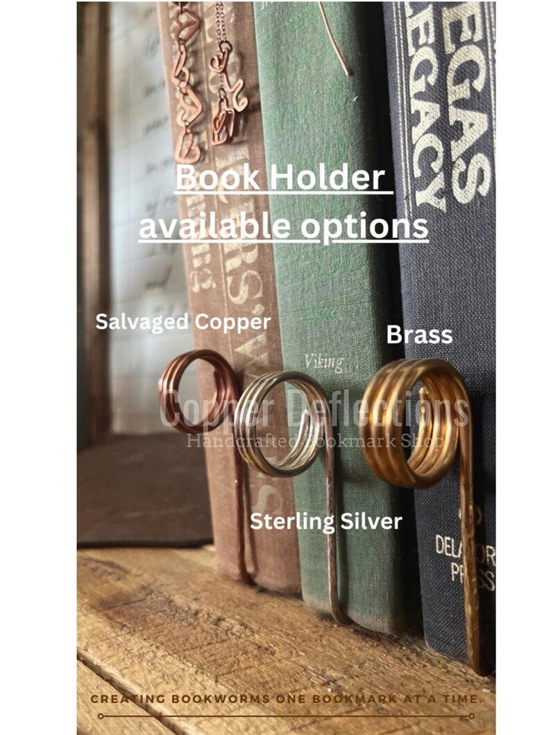 May include: Book holder made of wire in salvaged copper, sterling silver, and brass. The book holder is shown holding up a stack of books. The text "Book Holder available options" is visible at the top of the image. The text "Salvaged Copper", "Sterling Silver", and "Brass" are visible below the book holder.