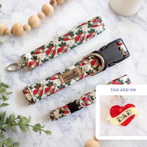 May include: Cream-colored dog collar and leash set with a repeating tattoo-style heart and "DAD" design. The set includes a collar with a black buckle, a matching leash, and a tag add-on with a heart and wings.