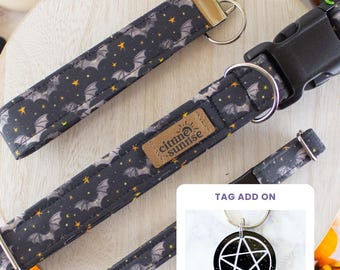 May include: A black fabric collar and matching keychain featuring a pattern of grey bats and yellow stars. The collar includes a black plastic buckle, a metal D-ring, and a tan label reading citrine sunrise. An inset shows a round black tag with a white pentagram.