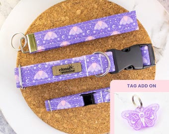 May include: A purple dog collar, leash, and tag set with a moth and moon pattern. The collar has a black buckle, and the leash has a gold metal clasp. The tag is butterfly-shaped and has a glittery finish. The brand name "citrine sunrise" is on the collar.