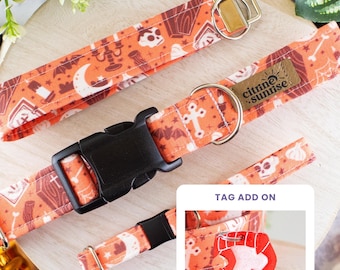 May include: An orange pet collar featuring a repeating pattern of skulls, coffins, bats, moons, and candles. The collar has a black plastic buckle, a silver metal D-ring, and a brown leather tag labeled Citrine Sunrise. Includes a red vampire teeth tag.