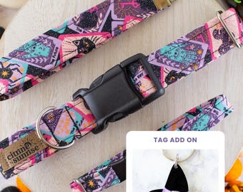 May include: A fabric pet collar featuring a repeating pattern of black cats, spiders, and mystical symbols in shades of purple, pink, and teal. It includes a black plastic buckle, a metal D-ring, and a tag add-on showing a black witch hat charm.
