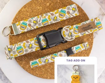 May include: A fabric wristlet, a dog collar with a black plastic buckle and a brown brand tag reading Citrine Sunrise, and a matching leash, all featuring a pattern of bees, honey jars, and flowers. Includes a bear-shaped tag add-on.