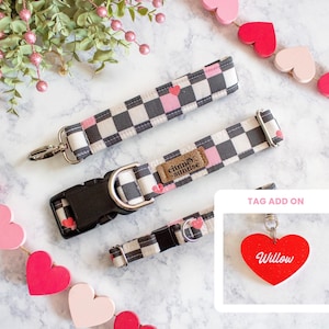 May include: Dog collar and leash set with a black and white checkered pattern, accented with pink hearts. Includes a matching tag with the name "Willow" on a red heart. The set is designed for pets.