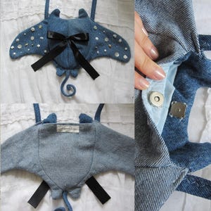May include: A blue denim manta ray bag with a black ribbon bow and white pearl embellishments. The bag has a magnetic closure and a small tag that says "Sew Much Cuteness".