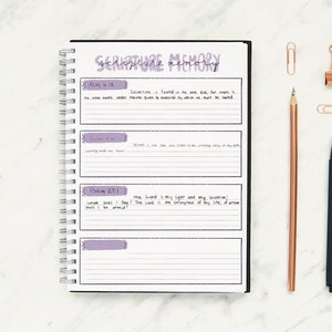 May include: A black and white spiral bound journal with the title "Scripture Memory" written in black cursive. The journal has three pages visible, each with a different Bible verse written in black cursive. The verses are Acts 4:12, Psalm 91:1, and Psalm 27:1.