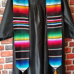 May include: Black graduation gown with a colorful striped stole. The stole has a tassel at the end.