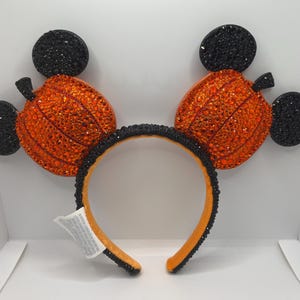 May include: Black and orange pumpkin-shaped Mickey Mouse ears with rhinestones.