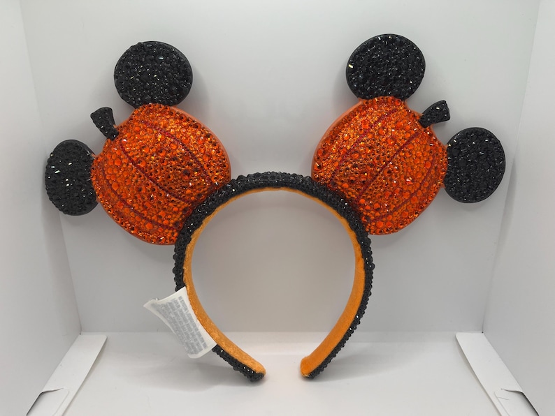May include: Black and orange pumpkin-shaped Mickey Mouse ears with rhinestones.
