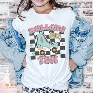 May include: White t-shirt with a graphic of a roller skate with the text "Rolling into Ten" in a retro style.