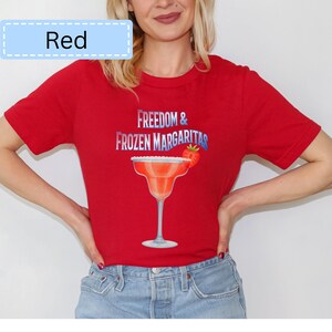 May include: Red t-shirt with the text "Freedom & Frozen Margaritas" and a margarita glass graphic. The margarita glass has a strawberry garnish. The word "Red" is in a light blue box in the upper left corner.