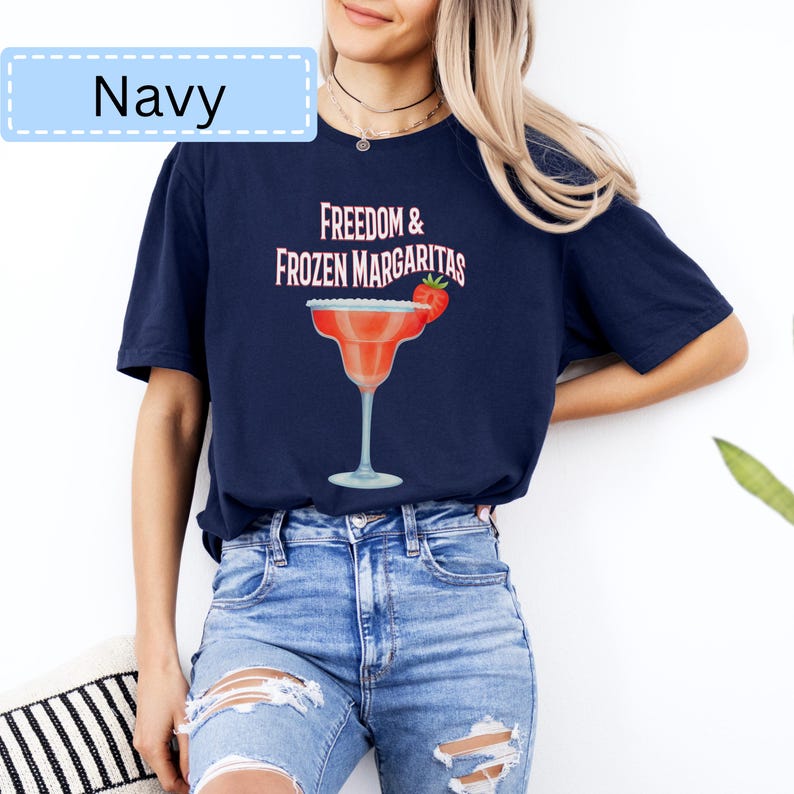 May include: Navy blue t-shirt with the text "Freedom & Frozen Margaritas" and a graphic of a margarita glass with a strawberry. The shirt also has the word "Navy" in a light blue box.