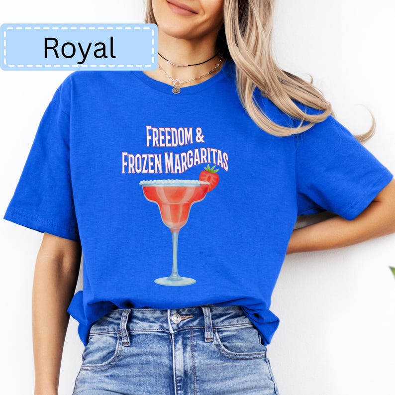 May include: Royal blue t-shirt with the text "Freedom & Frozen Margaritas" and a margarita glass graphic. The margarita glass is red with a strawberry garnish. The word "Royal" is in a light blue box.