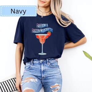 May include: Navy blue t-shirt with the text "Freedom & Frozen Margaritas" and a margarita glass graphic. The margarita glass is red with a strawberry garnish. The word "Navy" is in a light blue box at the top left.