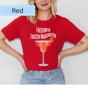May include: Red t-shirt with the text "Freedom & Frozen Margaritas" and a margarita glass graphic. The margarita glass has a strawberry garnish. The word "Red" is in a light blue box in the upper left corner.