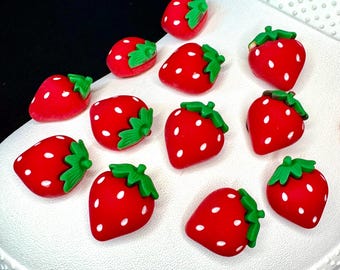 May include: A white shoe with red and green strawberry charms attached to it.