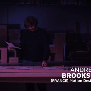 May include: A person standing at a wooden table, reviewing papers. The scene is dimly lit with a purple hue. Text on the table reads "ANDREY BROOKS (FRANCE) Motion Designer."