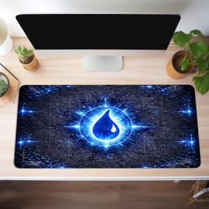 May include: A rectangular desk mat featuring a blue water drop design within a glowing circular emblem. The mat has a dark, textured background with radiating lines and bright blue accents. The design is centered on the mat.