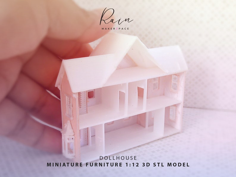 May include: A white, three-story dollhouse model with open interior spaces and window cutouts. The miniature house is held in a hand, with the text "Rain Maker Space" and "DOLLHOUSE MINIATURE FURNITURE 1:12 3D STL MODEL" visible.