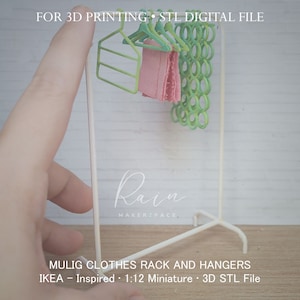 Può includere: Un appendiabiti in metallo bianco con grucce verdi e un capo di abbigliamento rosa. L'appendiabiti è un modello in miniatura in scala 1:12 ispirato all'appendiabiti MULIG di IKEA. Il testo "FOR 3D PRINTING - STL DIGITAL FILE" e "Rain MAKERSPACE" sono visibili nell'immagine. Il testo "MULIG CLOTHES RACK AND HANGERS" e "IKEA - Inspired 1:12 Miniature - 3D STL File" sono anche visibili nell'immagine.