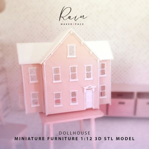 May include: A pink dollhouse miniature with a white roof and window frames. The dollhouse is on a small pink table. The text "Rain MAKER2PACE" is at the top, and "DOLLHOUSE MINIATURE FURNITURE 1:12 3D STL MODEL" is at the bottom.
