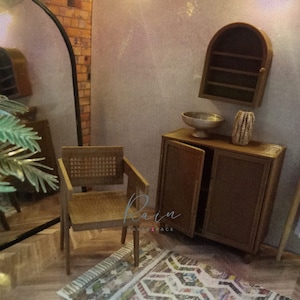 May include: A miniature living room set with a brown wicker chair, a wooden cabinet with two doors, a small arched shelf, a silver bowl, and a brown vase. The set is on a rug with a colorful geometric pattern.