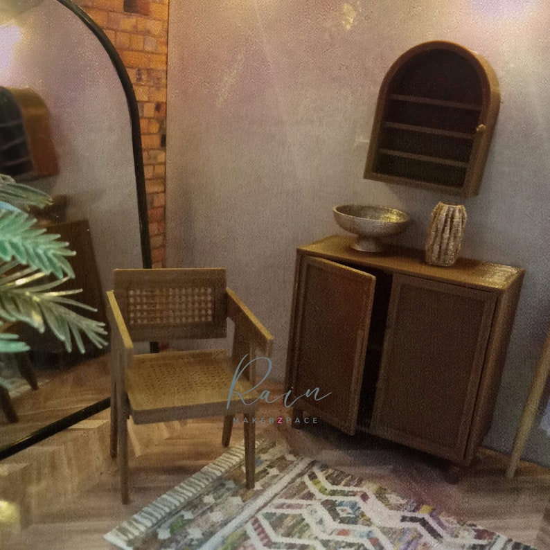 May include: A miniature living room set with a brown wicker chair, a wooden cabinet with two doors, a small arched shelf, a silver bowl, and a brown vase. The set is on a rug with a colorful geometric pattern.