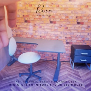 K&ouml;nnte beinhalten: Ein grauer Miniatur-Ecktisch mit einem wei&szlig;en Stuhl und einem grauen Nachttisch mit zwei Schubladen. Der Schreibtisch ist mit "IKEA-INSPIRED BEKANT CORNER DESK MINIATURE FURNITURE 1:12 3D STL MODEL" beschriftet.