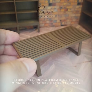 May include: A miniature brown wooden platform bench with a slatted top and a simple, modern design. The bench is a 1:12 scale model and is perfect for dollhouses or miniature furniture collections.  "GEORGE NELSON PLATFORM BENCH 1946 MINIATURE FURNITURE 1:12 3D STL MODEL" is printed on the surface.