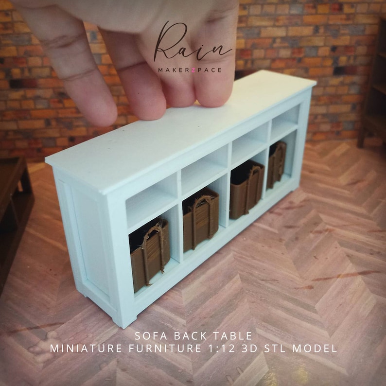 May include: A miniature white sofa back table with four cubby spaces, each containing a brown basket. The table is labeled "SOFA BACK TABLE" and "MINIATURE FURNITURE 1:12 3D STL MODEL". The Rain Maker Pace logo is in the upper right corner.