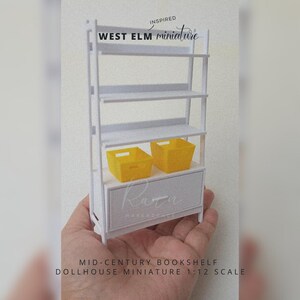 Pode incluir: Estante de livros em miniatura branca com uma gaveta e duas cestas de armazenamento amarelas. Inspirado em West Elm. Miniatura de casa de bonecas em escala 1:12.