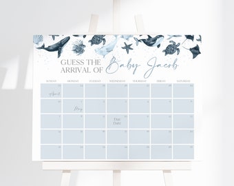 May include: A white sign featuring a calendar for April and May with the text GUESS THE ARRIVAL OF Baby Jacob. The top border displays blue watercolor illustrations of sea creatures including a whale, turtle, starfish, and stingray.