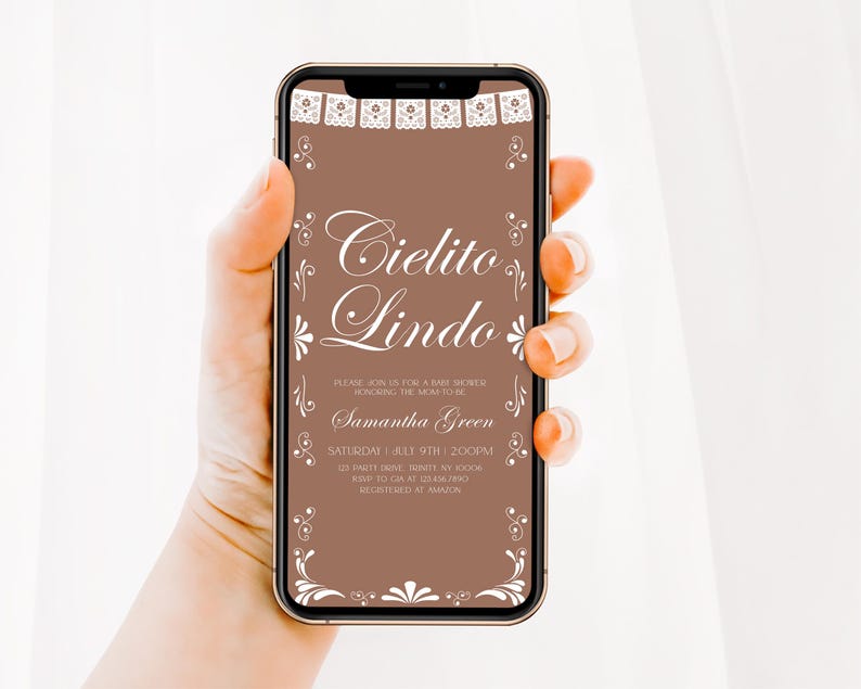 May include: A smartphone displaying a digital baby shower invitation on a brown background. The text reads Cielito Lindo, Please join us for a baby shower honoring the mom to be, Samantha Green, Saturday, July 9th, 2:00PM, 123 Party Drive, Trinity, NY, 10006, RSVP to Gia at 123-456-7890, Registered at Amazon. White decorative borders frame the top and bottom.