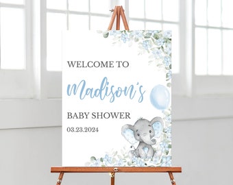 May include: Welcome to Madison's Baby Shower sign featuring a blue and grey elephant illustration, blue balloon, and floral design. The date is 08.23.2024.