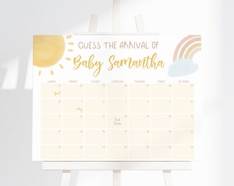 May include: A white rectangular sign featuring the text "GUESS THE ARRIVAL OF Baby Samantha" in brown and gold script. The design includes a yellow sun, a pastel rainbow with a blue cloud, and a calendar grid for April and May with "Due Date".