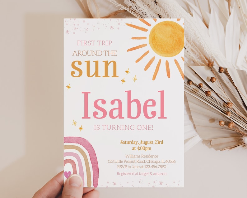 Pu&ograve; includere: Un invito di primo compleanno rosa e oro con un design a tema sole e arcobaleno. L'invito recita "Primo viaggio intorno al sole Isabel compie un anno!" e include i dettagli della festa, tra cui data, ora, luogo e informazioni RSVP.