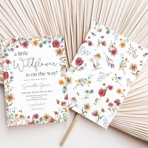 May include: A white baby shower invitation with a floral border. The text reads "a little Wildflower is on the way!" and includes the name "Samantha Green" and the date and time of the shower.