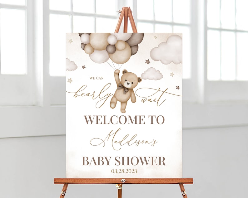 K&ouml;nnte beinhalten: Ein Willkommens-Schild f&uuml;r eine Babyparty mit einem braunen Teddyb&auml;r, der Ballons h&auml;lt. Das Schild lautet "We can bearly wait" und "Welcome to Maddison's Baby Shower 03.28.2023".