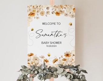 Op de afbeelding: Welkom bij Samantha's Baby Shower bord met een bloemmotief met gedroogde bloemen en bijen. Het bord is wit met zwarte tekst en de datum 10.28.2024.