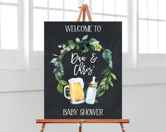 May include: A black chalkboard sign with a green wreath and the text "Welcome to Dan & Chris' Baby Shower". A beer mug and a baby bottle are in the center of the wreath.