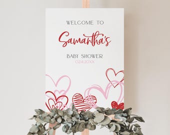 May include: Welcome to Samantha's Baby Shower sign with a pink and red heart design. The date of the shower is 021420XX.